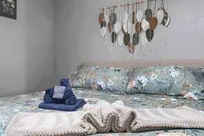 Une chambre à coucher avec un lit, des oreillers, une couverture et une décoration murale.