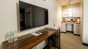 Una cocina con una amplia televisión de pantalla plana, una barra de madera y un microondas.