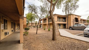 A building with multiple balconies, a parking area, and a tree in the courtyard.
