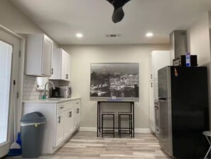 A kitchen with white cabinets, a black refrigerator, a microwave, and a coffee maker.