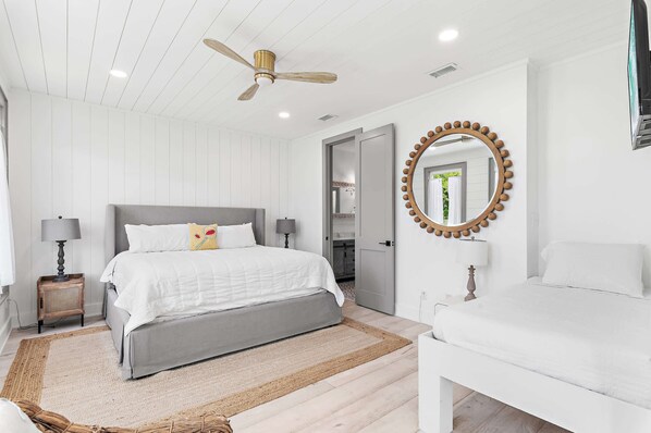 A bedroom with a bed, bedside tables, a mirror, and a ceiling fan. - Walk to the Beach + Close to Seaside | Gated Community | Pond Views - 'Peace of Mind' (Santa Rosa Beach)