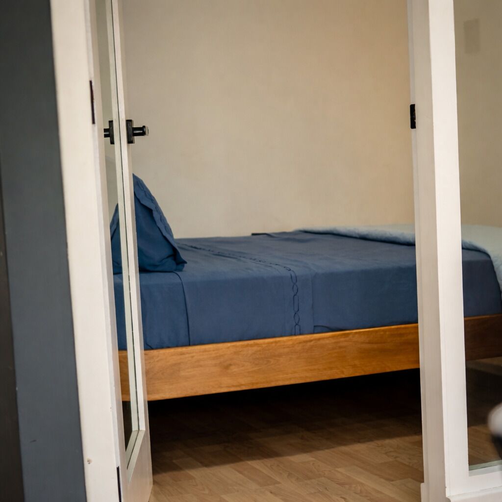 Ein Zimmer mit einem Bett, einer Tür und Holzboden.