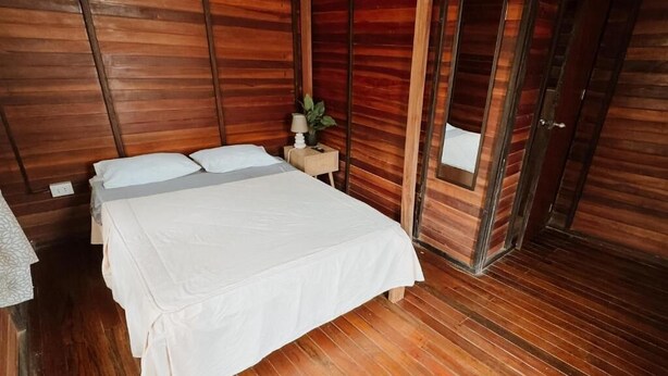 A wooden room with a bed, a nightstand, and a mirror. - CABAÑA CASA BLANCA HUACACHINA PERU ACCOMMODATION & TOURS (Huacachina)