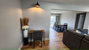 A modern living room with a sofa, a dining table with chairs, and a vase with dried plants. - Spacious Remodeled Home with Huge Backyard (Denison)