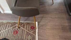 Ein kleiner, moderner Raum mit einem runden Tisch, zwei grauen Stühlen und einem gemusterten Teppich.