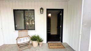 A porch with a wooden chair, potted plants, a welcome mat, and a staircase leading inside. - Farmhouse Loft with pond + pasture views in Creal Springs (Creal Springs)