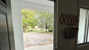 A door with a 'WELCOME' mat, a view of a driveway, and a wall-mounted basket. - Farmhouse Loft with pond + pasture views in Creal Springs (Creal Springs)