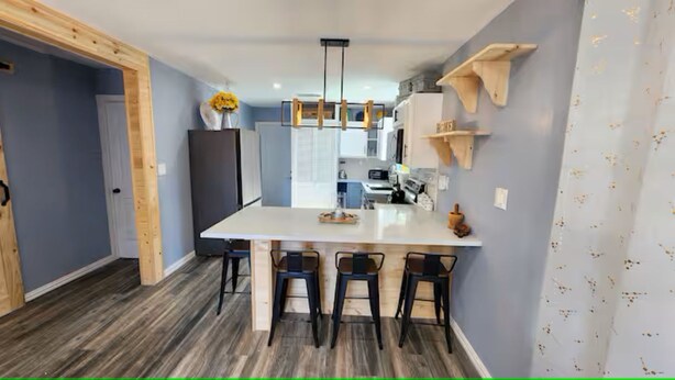 Una cocina moderna con una isla central, taburetes de bar, detalles de madera y un horno empotrado.