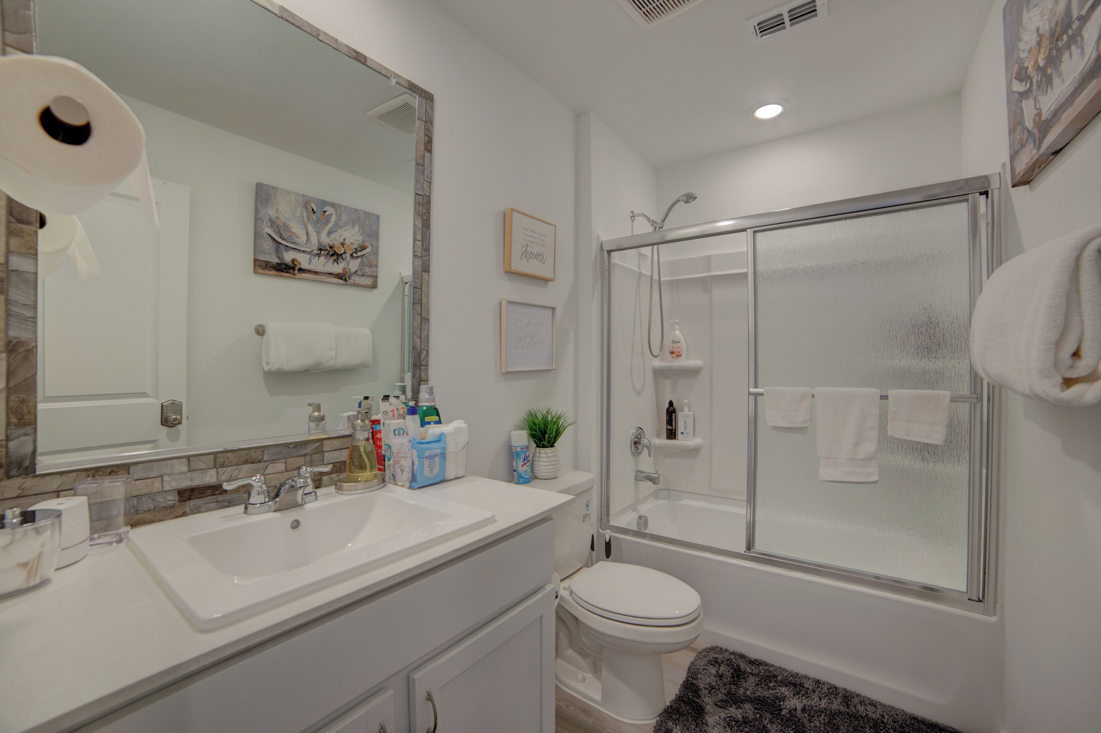 Un bagno con doppio lavandino, toilette, box doccia in vetro e uno specchio grande.