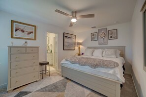 Een slaapkamer met een bed, een dressoir, een plafondventilator en kunstwerken aan de muur.