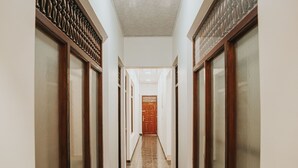 A corridor with a tiled floor, wooden doors, and a ceiling light.