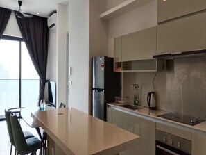 A modern kitchen with a dining area, including a refrigerator, stove, and seating. - 2-bedroom apartment in beautiful Kuala Lumpur with AC and gym access (Kuala Lumpur)