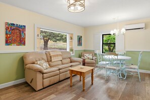 Ein Wohnzimmer mit einer Couch, einem Esstisch mit Stühlen, einer Kronleuchter und Bildern an den Wänden.