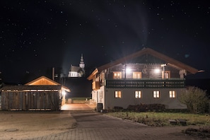 Ein großes, hell erleuchtetes Gebäude mit vielen Fenstern und einem markanten Turm im Hintergrund.
