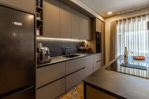 A modern kitchen with a built-in espresso machine, a sink, and a dining area with a table set for two.
