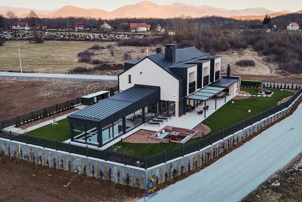 Une maison moderne dotée d’un grand patio, d’une piscine et offrant une vue sur les montagnes.