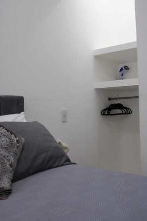 A bedroom with a bed, a nightstand, a wall-mounted shelf with a coat rack, and a power outlet. - Bowra Suite Familiar, Zona Consulado (Zapopan)