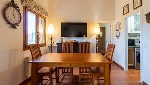Un comedor con una mesa de madera, sillas, un reloj de pared y un televisor.