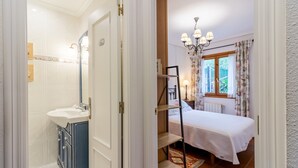 Un dormitorio con cama, mesita de noche, cómoda y ventana con cortinas.