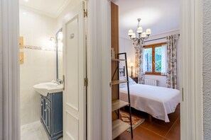 Une chambre à coucher avec un lit, une table de chevet, une commode et une fenêtre avec des rideaux.