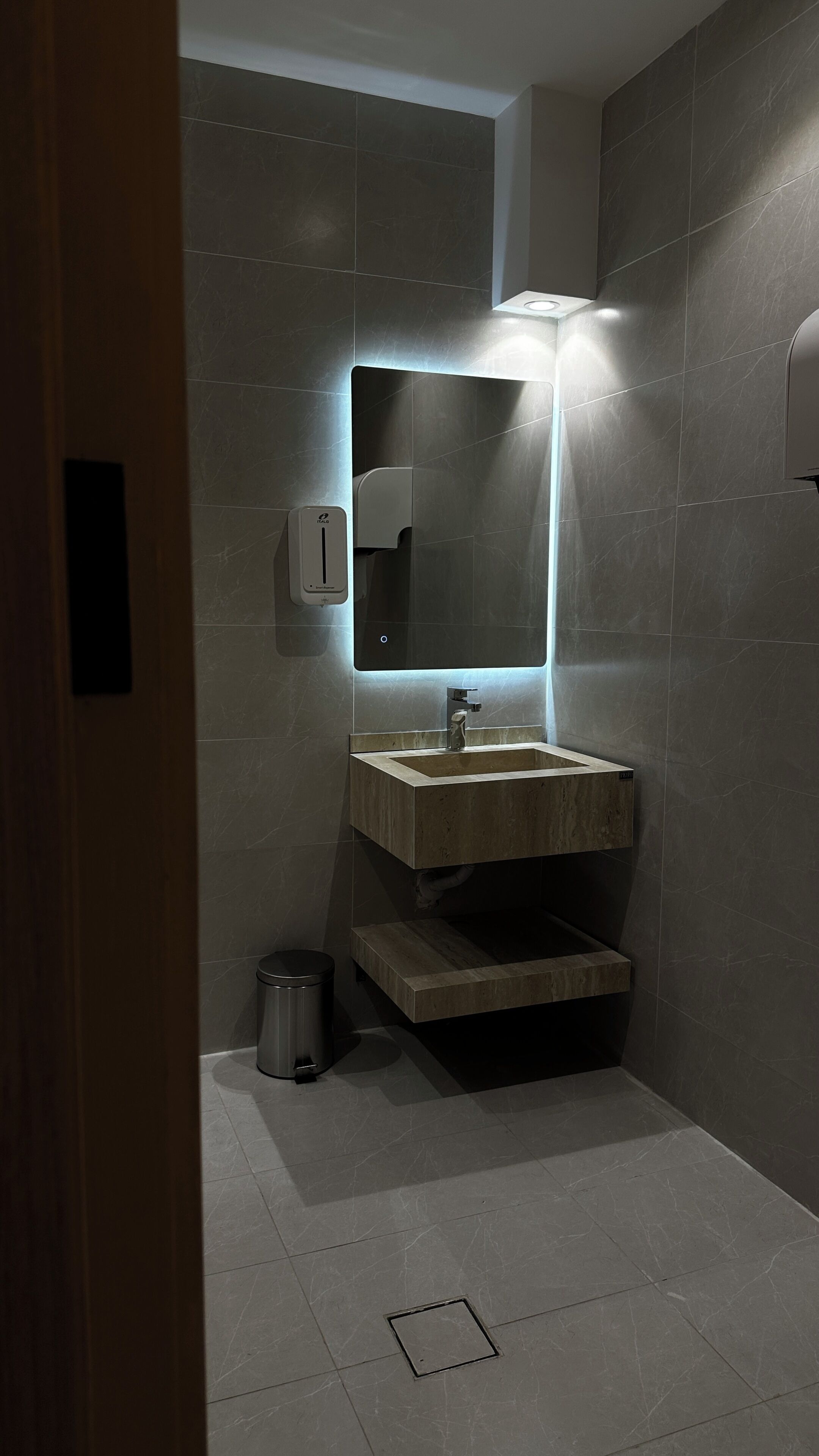 A modern bathroom with a rectangular sink, a mirror, and a hand dryer.