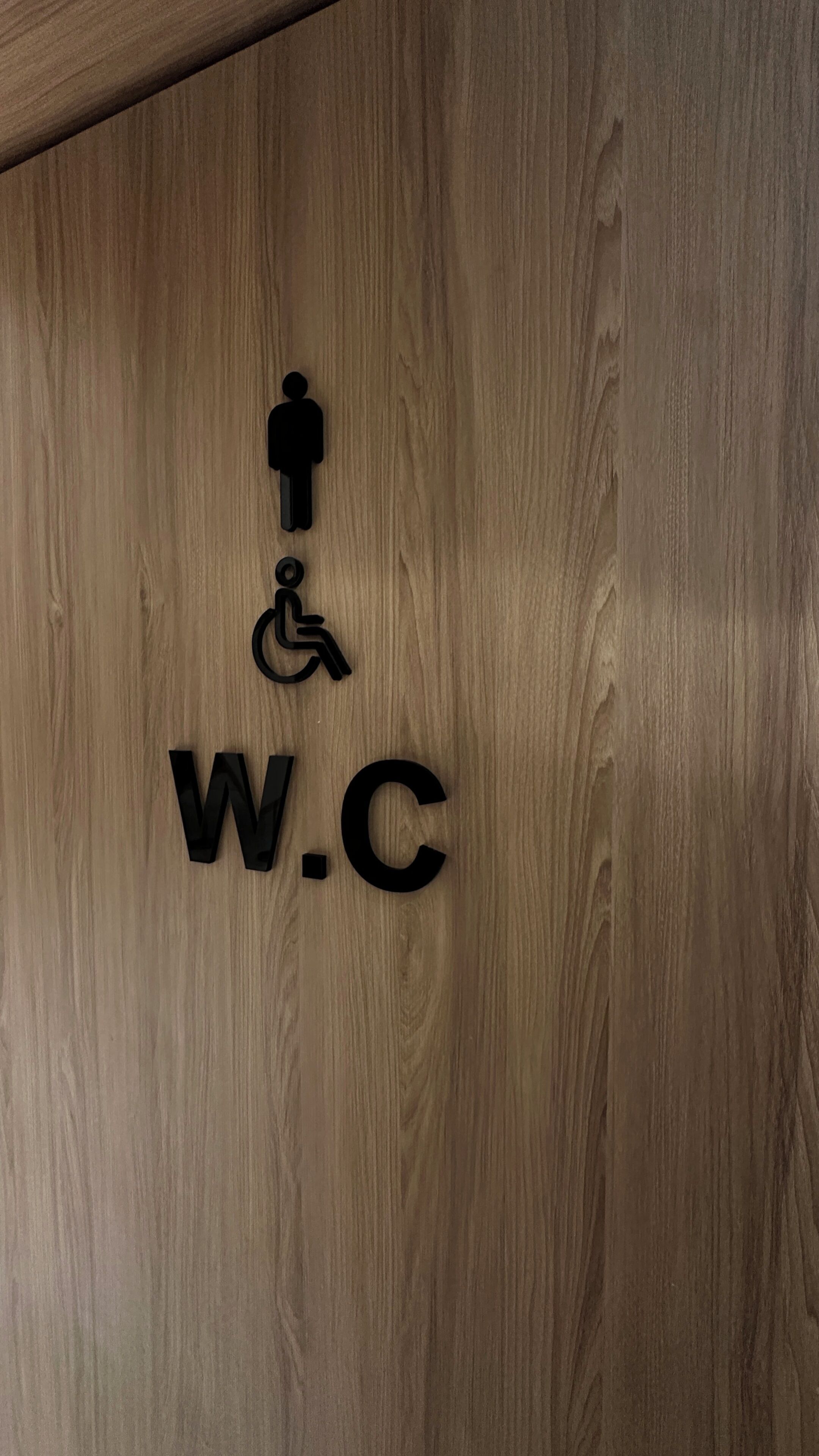 A wooden wall with a sign indicating a restroom and a wheelchair symbol.