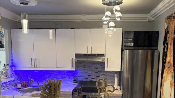 Una cocina moderna con una isla central, electrodomésticos de acero inoxidable y detalles decorativos.
