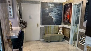 Amplia habitación con piso de baldosas, zona de comedor con barra y sillas, un sofá y un cuadro abstracto grande en la pared.