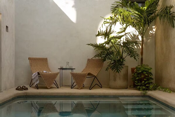 A poolside area with two wicker chairs, a small table, and a potted plant. - Casa Meridiano 48, 2-Bedroom Accommodation (Mérida)