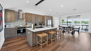 Una cocina moderna con armarios de madera, una isla grande con taburetes y vistas al exterior.