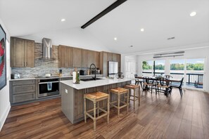 Una cocina moderna con armarios de madera, una isla grande con taburetes y vistas al exterior.