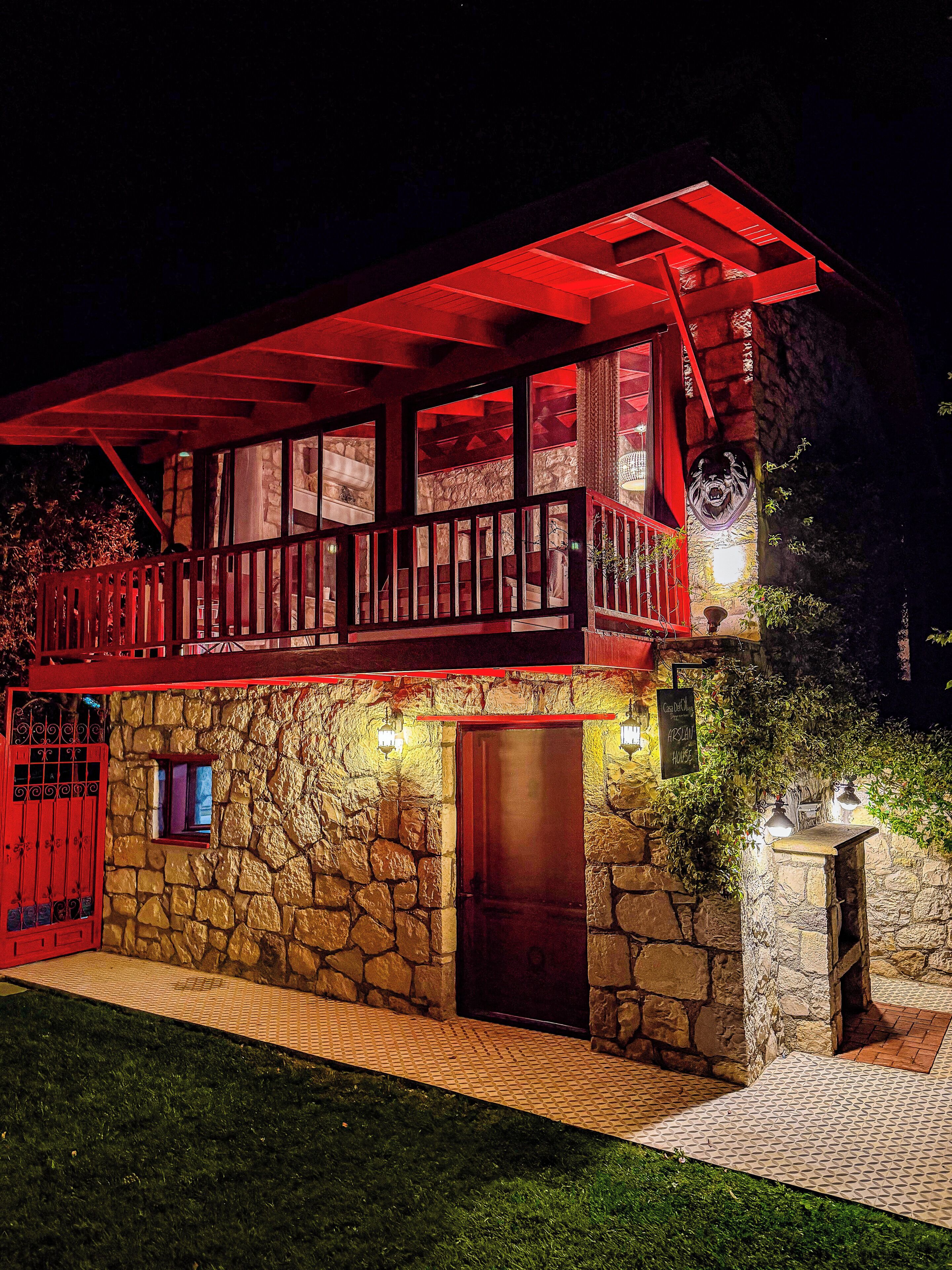 A two-story stone building with a red balcony and a stone entrance.