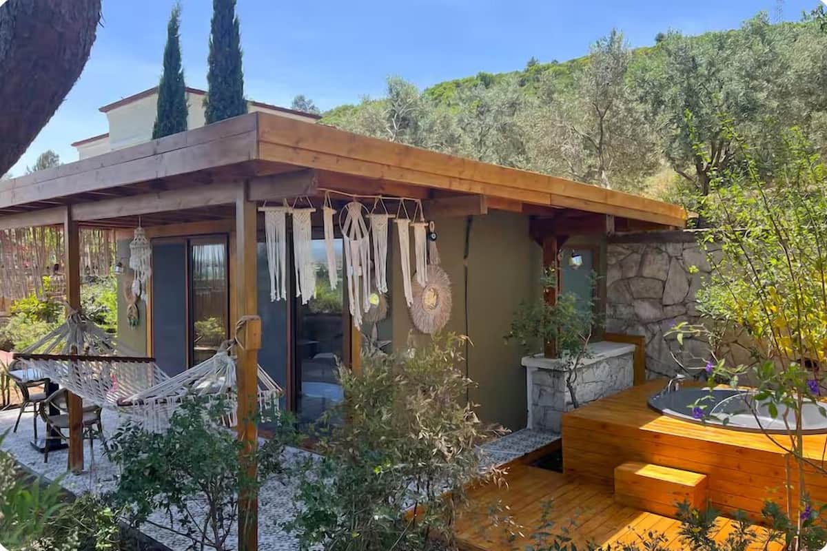 A modern house with a wooden deck, a hot tub, and a hammock.