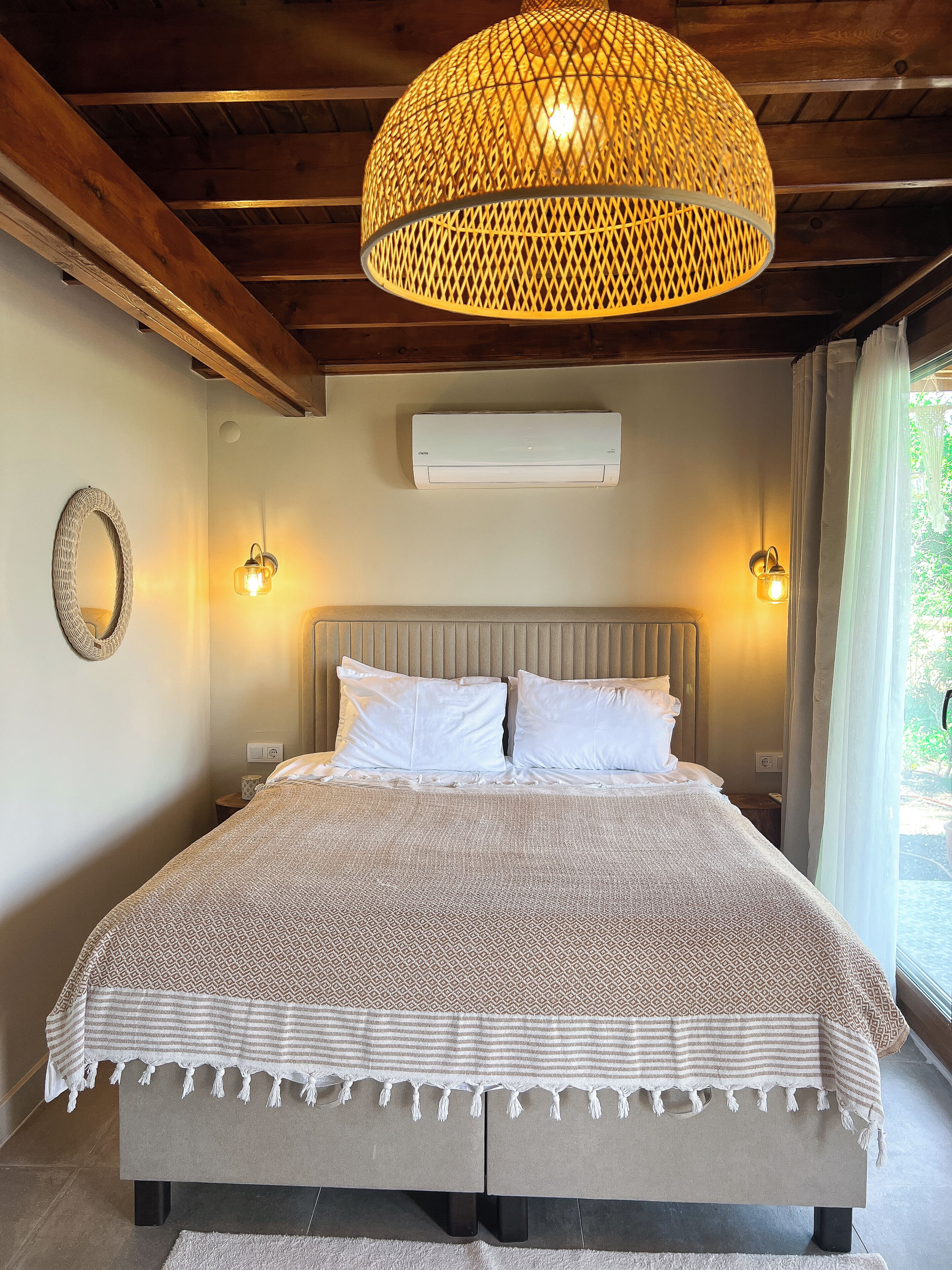 Un dormitorio con cama, ventilador de techo, equipo de aire acondicionado y ventana con cortinas.