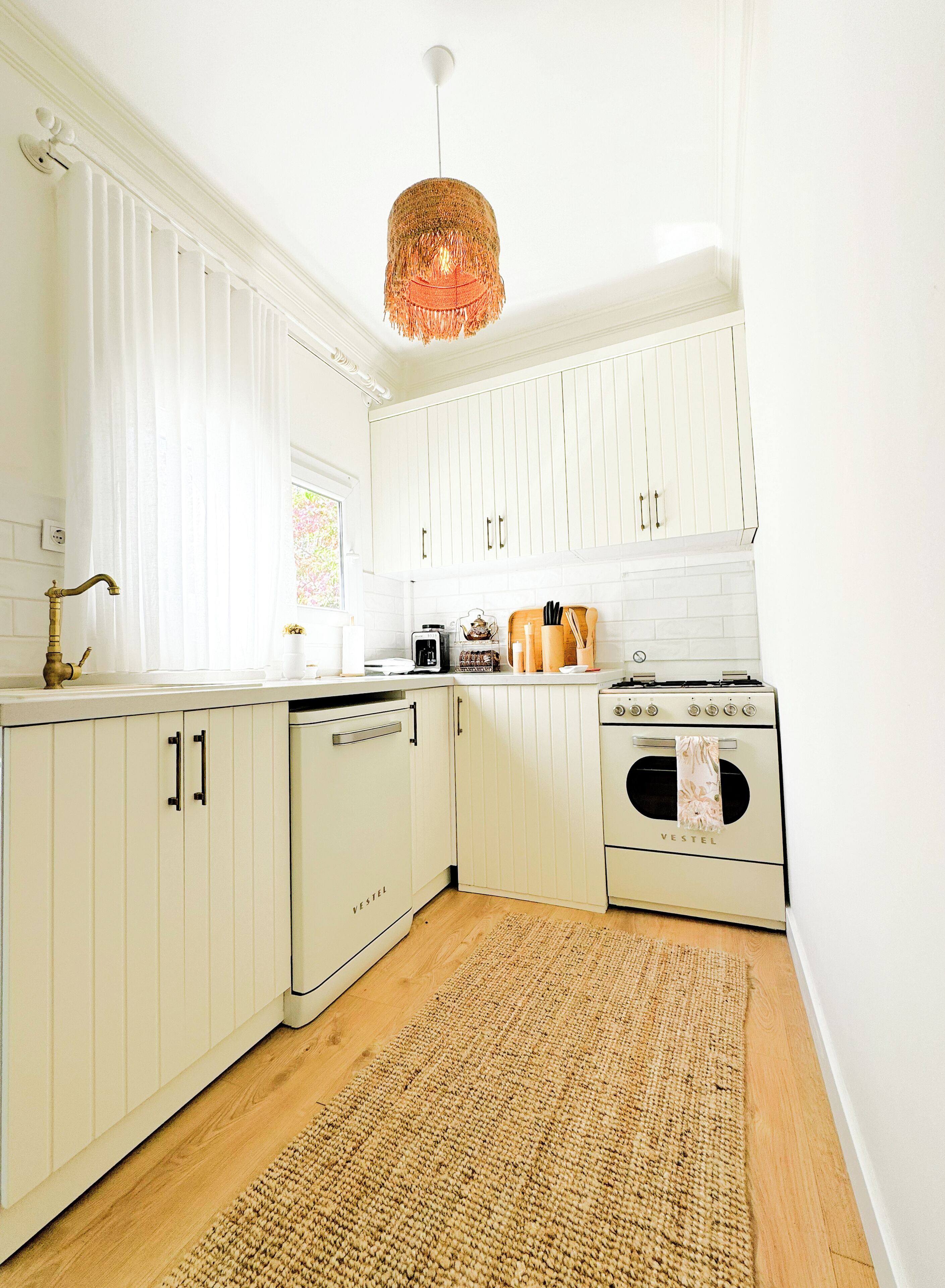 A kitchen with white cabinetry, a wooden floor, and a hanging light fixture.