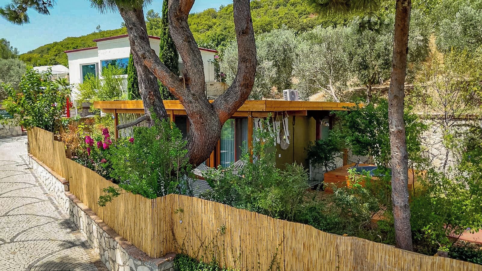 A modern house with a wooden fence, a hammock, and a garden.