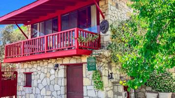Une maison en pierre avec un balcon rouge, un mur de pierre et une enseigne indiquant « Maison Arslan ».