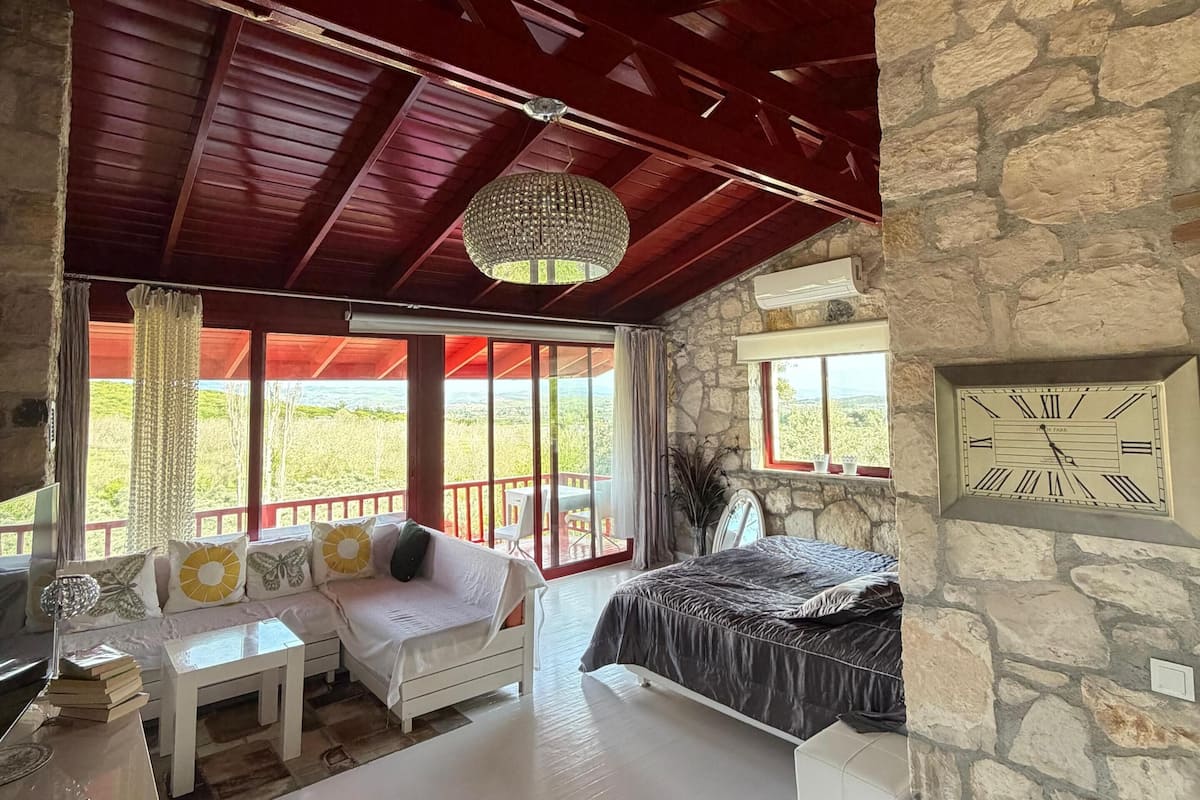 A room with a bed, a sofa, a table, and a chandelier.