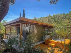 Una cabaña de madera con fachada de piedra, una terraza de madera y un jacuzzi.
