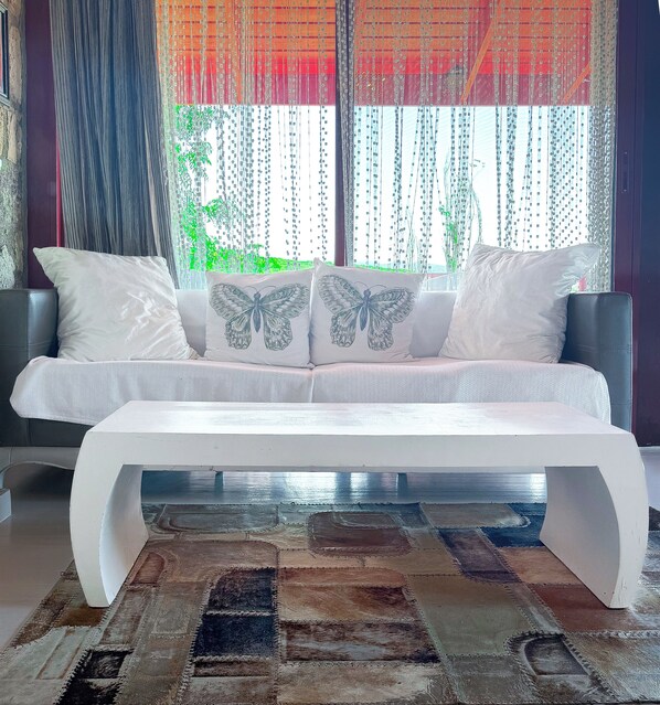 A modern living room with a white sofa, butterfly-patterned cushions, and a patterned rug.