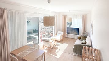 A spacious living area with a dining table, chairs, a sofa, and a TV.