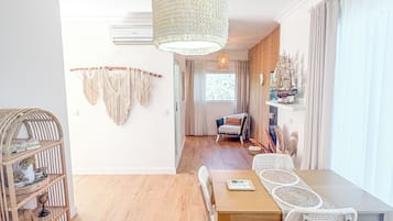 Un coin repas avec une table en bois et des chaises en osier, un luminaire suspendu et une décoration murale en macramé.