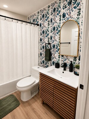 A bathroom with a toilet, sink, mirror, and shower curtain.