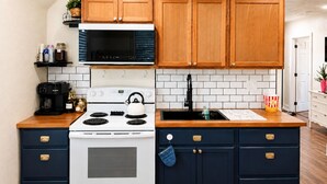 Una cocina con armarios de madera, una estufa blanca, un microondas negro y un salpicadero de azulejos.