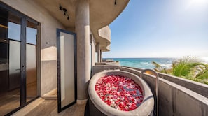 A balcony with a large bathtub filled with rose petals, a door, and a view of the ocean. - Oceanfront 4BR Duplex in Maiim Tankah w/Pool & Gym (Tulum)