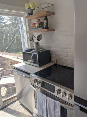 Une cuisine équipée d’un four à micro-ondes, d’une cuisinière, d’un four et d’une fenêtre donnant sur une terrasse.