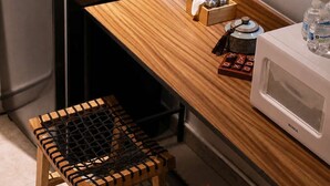 Une cuisine compacte avec un réfrigérateur noir, un four à micro-ondes et une table en bois accompagnée de deux tabourets.