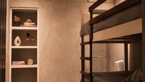 Une chambre avec un lit superposé et une étagère intégrée où sont rangés des livres et des objets décoratifs.