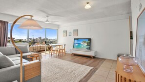 A modern living room with a sofa, TV, and dining area. - Kailoha Unit 8, 27 Canberra Tce, Kings Beach (Kings Beach)