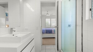 Ein modernes Badezimmer mit einem weißen Waschbecken, einem Spiegel und einer Dusche.